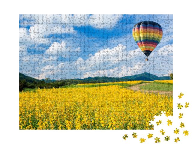Puzzle de 1000 pièces « Montgolfière au-dessus de champs de fleurs jaunes, à l'arrière-plan une moyenne montagne »