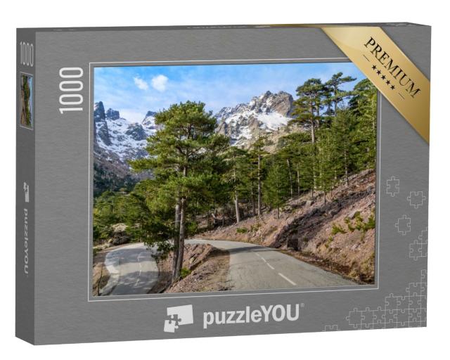 Puzzle de 1000 pièces « Route sinueuse à travers une forêt de pins devant une chaîne de montagnes enneigées »